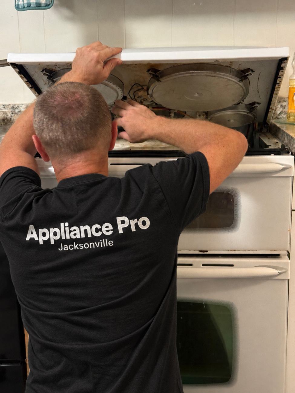 Appliance Pro technician repairing a range in a Jacksonville home